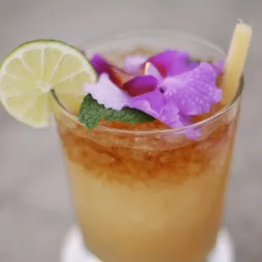 a glass of Kentucky Joe garnished with a slice of lime and flowers