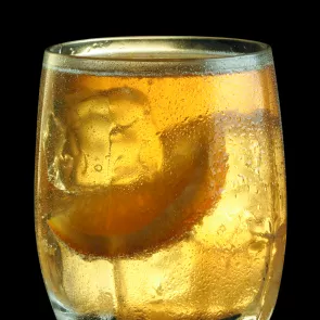 Glass of Maker's Mark® Summer Breeze with ice cubes and orange wedge.