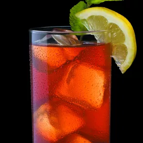 Glass of Maker's Mash with ice cubes, garnished with mint leaves and a lemon slice.