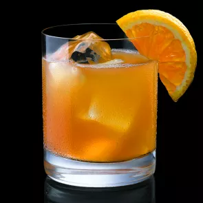 Glass of Maker's Mistletoe with ice cubes, garnished with an orange wedge.