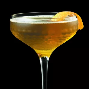 Glass of The Fiscal Agent garnished with orange peel.