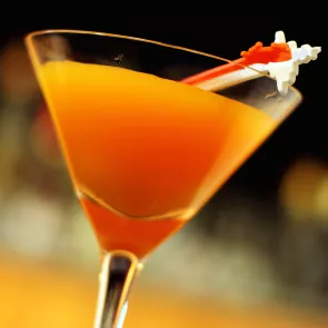 A cocktail glass of Cran Tropic-Tini, adorned on a cocktail pick.