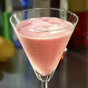 A martini glass of Vanilla Cream Berry-Tini garnished with raspberries.