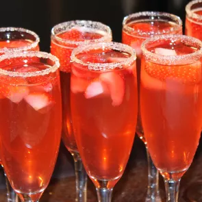 A glass of Sauza® strawsberry Sparkler, garnished with a wedge of lime and sugar on the rim of the glass