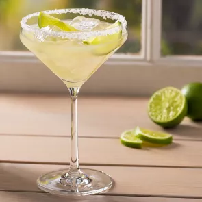 A glass of Sauza® Classic Margarita garnished with lemon slices and salt alongside few lime slices