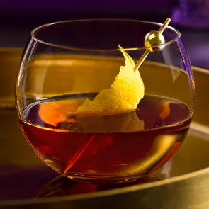 Glass of Courvoisier® Classic garnished with lemon peel on a steel tray.