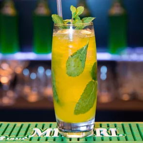 a glass with a Midori® Jim and Ginger garnished with mint leaves and straw