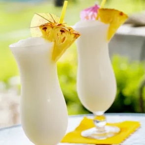 Two glasses of Cruzan® Colada garnished with pineapple slice and cocktail umbrella