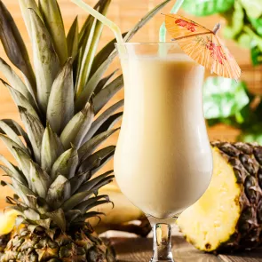 A glass of Amaretto Pina Colada, decorated with a cocktail umbrella on the rim of the glass and a straws