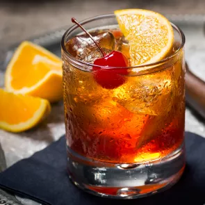 a glass of Bourbon Cider Cocktail with orange slices and a cherry on top