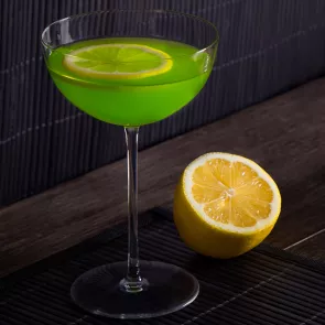 Glass of Holly Jolly garnished with lemon slice alongside half lemon