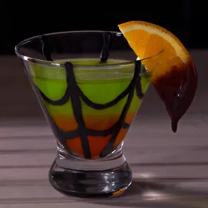 Chocolate web drawn in a glass of Spider's Kiss garnished with a chocolate-dipped orange slice.